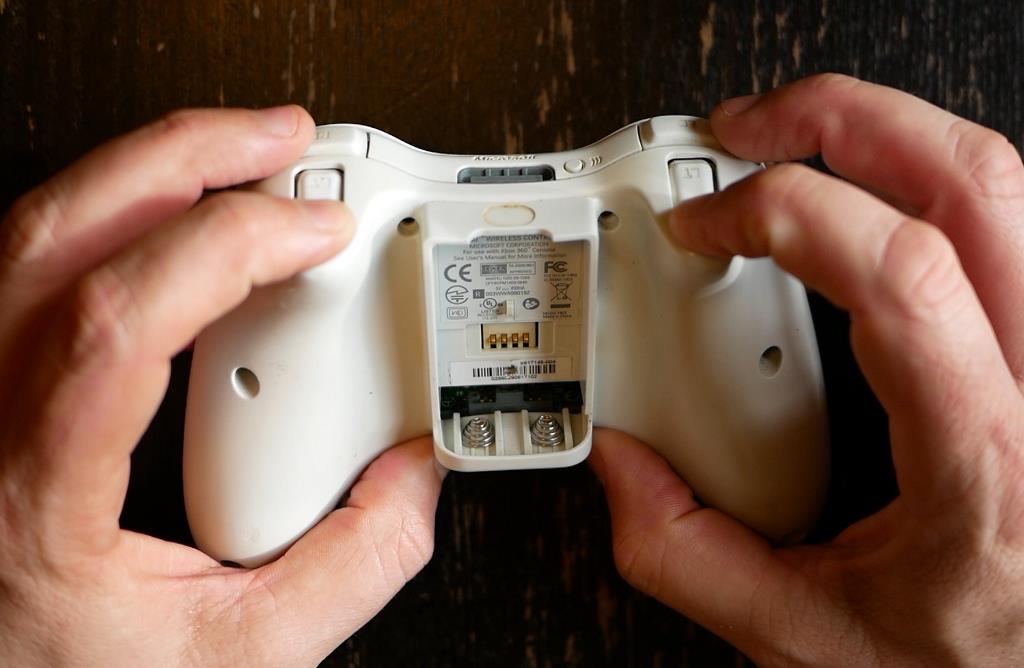 Photo d'une manette Xbox 360, appui sur les deux gâchettes pour dégager la coque arrière