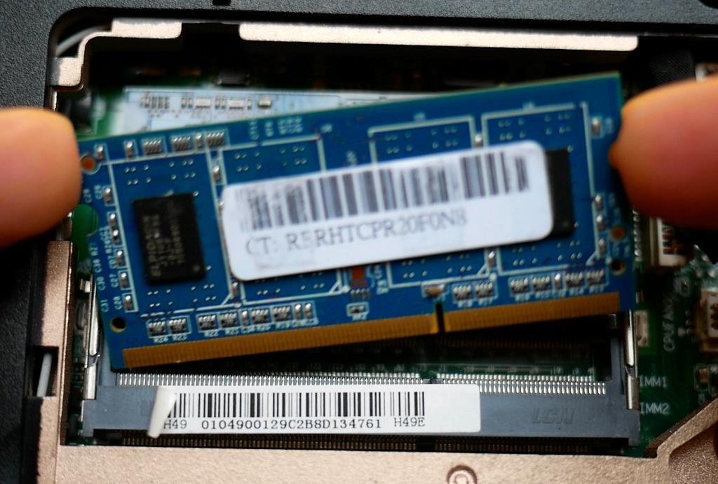Photo d'une barrette mémoire DIMM en train d'être retirée de son slot