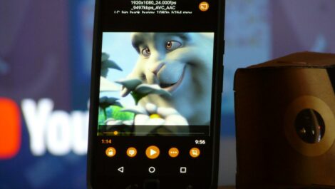 Photo d'un smartphone avec l'application VLC à côté d'une visionneuse Cardboard. YouTube en fond.