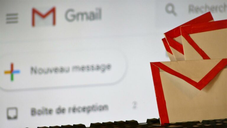 Photo d'envellopes papier aux couleurs de Gmail posées sur un clavier d'ordinateur avec site Gmail en arrière plan.